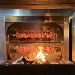 Rotsserie chicken being grilled right next to our table