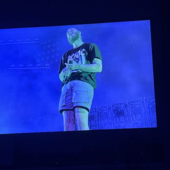 BATTER - Post Malone concert. - A person is on stage, illuminated by blue light, holding a microphone, with their head tilted back and eyes closed. - Desserts Near Me - Hammond, Louisiana