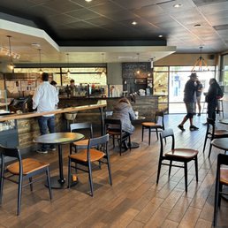 people in a coffee shop with tables and chairs people in a coffee shop with tables and chairs