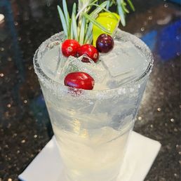 a cocktail with cranberries and rosemary garnish