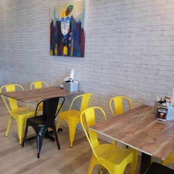 Honest - a dining room with yellow chairs and a painting on the wall - Sandwiches Near Me - Clifton, New Jersey
