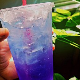  a hand holding a cup of blue liquid