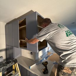 Alex is installing upper cabinets, ensuring everything is tight, leveled, and on measurement