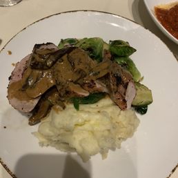 Pork loin with a mushroom cream sauce, mashed potatoes, and Brussels sprouts