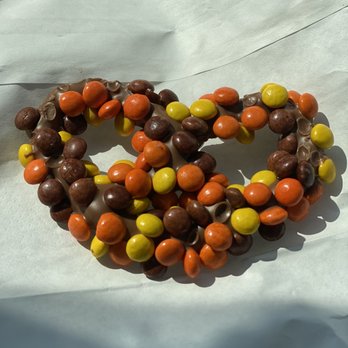 Abbate Bakery - A beaded bracelet composed of orange, yellow, and brown beads, arranged in a circular pattern, placed on white paper. - Bakeries Near Me - Matawan, New Jersey