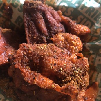 Wingstop - Wingstop has thighs, small but tasty !!! Ordered via Door Dash. Not sure if you can order these in the store. - Fried chicken wings with seasoning and spices are shown in a basket lined with branded paper, likely from a restaurant or takeout order. - Chicken Wings Near Me - Hurst, Texas