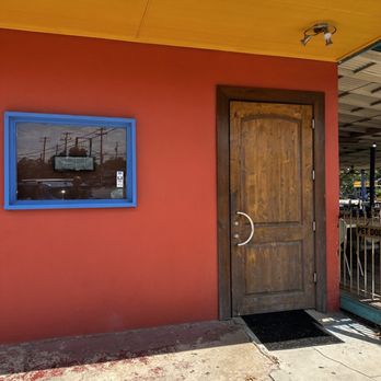 Sazón - a red building with a wooden door and a blue window - Mexican Near Me - Austin, Texas