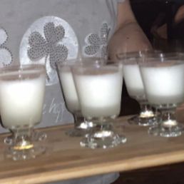 a woman carrying a tray with glasses of milk