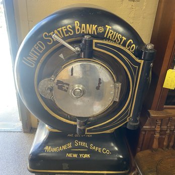 Antique Warehouse - A large, antique vault door with gold lettering and black paint, labeled 'United States Bank and Trust Co.' and 'Manganese Steel Safe Co., New York,' displayed indoors. - Antiques Near Me - Albuquerque, New Mexico