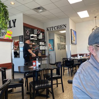 Weck's - Entrance to kitchen - The image shows a restaurant interior with black chairs and tables, a kitchen entrance labeled 'KITCHEN,' and a staff member near the counter. - Breakfast & Brunch Near Me - Albuquerque, New Mexico