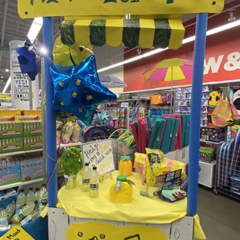 Five Below - A small lemonade stand setup with a yellow sign, balloons, and bottles, located inside a retail store with various products in the background. - Discount Store Near Me - El Monte, California