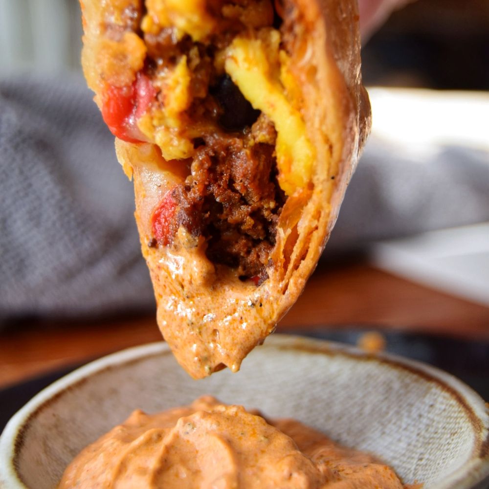 4 Birds Bakery - a hand holding a burrito with a bite taken out of it - Bakeries Near Me - Indianapolis, Indiana 4 Birds Bakery - a hand holding a burrito with a bite taken out of it - Bakeries Near Me - Indianapolis, Indiana