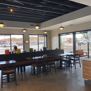 Starbucks - Seating area. - A coffee shop interior featuring tables and chairs along large windows, with ceiling lights and a counter area. - Coffee & Tea Near Me - Gallup, New Mexico