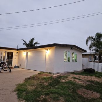 All - Conditions Construction - a house with a garage and a bike parked in front of it - General Contractors Near Me All - Conditions Construction - a house with a garage and a bike parked in front of it - General Contractors Near Me