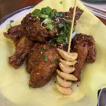 Tiger Mama - Honey soy garlic - Fried chicken pieces topped with chopped green onions and sesame seeds, served with a garlic skewer, on a yellow paper-lined tray. - Korean Near Me - Eugene, Oregon