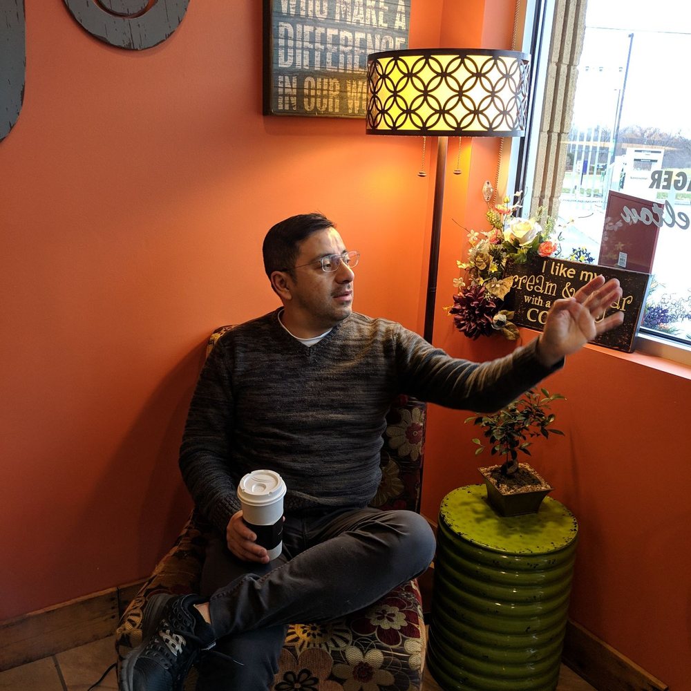 a man sitting in a chair holding a cup of coffee