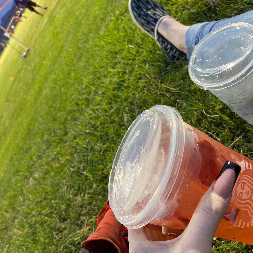 a person sitting on the grass holding a drink a person sitting on the grass holding a drink