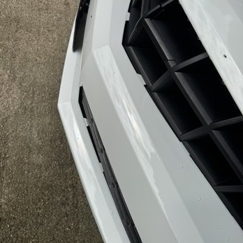 Perfect Touch Performance - He couldn't even put the bumper back on. - A white vehicle's front bumper and grille are captured in the image, with the bumper appearing smooth and clean. The black grille features a geometric pattern, and the photo is taken at an angle showing part of the ground surface nearby. The image emphasizes the vehicle's exterior details and condition. - Auto Repair Near Me - Westminster, Maryland