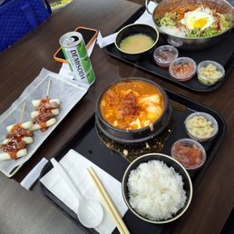 Rice cakes with sausages, kimchi tofu soup, bibimbap, and plenty of side dishes. Rice cakes with sausages, kimchi tofu soup, bibimbap, and plenty of side dishes.