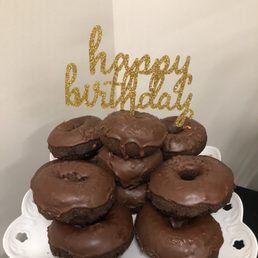 chocolate frosted doughnuts on a plate with a happy birthday sign