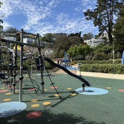 Sunnyside Recreation Center - Wide view of Sunnyside Park playground with climbing structure, slide, and soft rubber flooring.