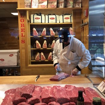 Lobel's - a butcher cutting meat on a cutting board - Butcher Near Me - Bronx, New York