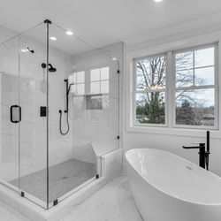 W Kitchen & Bath - Natural light highlights the seamless glass shower and elegant freestanding tub.
