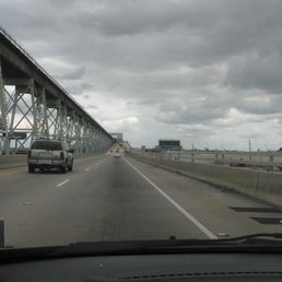 Roadway to the bridge. To the left is a train bridge.