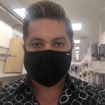 Alien Brew Pub - A person with styled hair and a patterned shirt is wearing a black face mask in an indoor setting, possibly a store or public space. - Burgers Near Me - Albuquerque, New Mexico