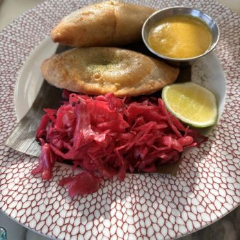Sly Rooftop Bar - Doro wat empanada - Ethiopian cuisine featuring two fried pastries, pink cabbage, lemon wedge, and a small bowl of yellow sauce on a decorative plate. - Breakfast & Brunch Near Me - Washington, DC, District of Columbia