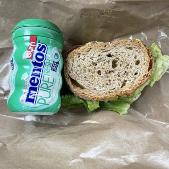 Beach Pea Baking Co - A sandwich with a slice of bread and lettuce is placed on brown paper, next to a container of Mentos Pure Fresh gum. - Bakeries Near Me - Kittery, Maine
