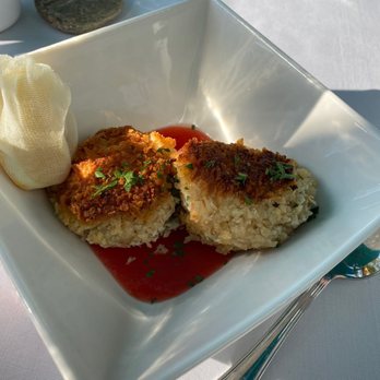 Blu - Crab puffs appetizer - Breaded whitefish fillets are presented in a white square bowl, garnished with chopped herbs and served with tomato sauce. - French Near Me - Glen Arbor, Michigan