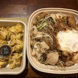 Steamed shumai and pad Thai with chicken, tofu, and fried egg - A takeout container holds steamed shumai with soy sauce, alongside a larger container of pad Thai with chicken, tofu, bean sprouts, and a fried egg.