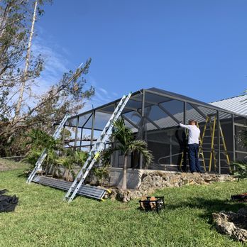 Key Screening - a man standing on a ladder in front of a house - General Contractors Near Me - Fort Myers, Florida