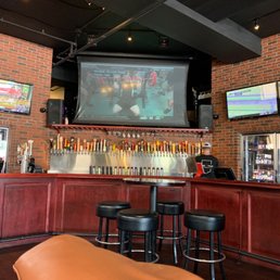 a bar with stools and televisions