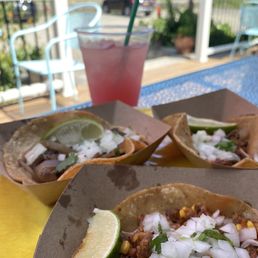 two tacos on a table with a drink in the background two tacos on a table with a drink in the background