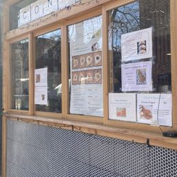 Conohen's exterior features a wooden-framed window with menu signs and promotional notices, located in Brooklyn, NY.