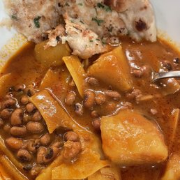 Aloo Tama, delightful - A close-up of a bowl containing lentil and potato curry with a piece of naan bread, garnished with herbs.