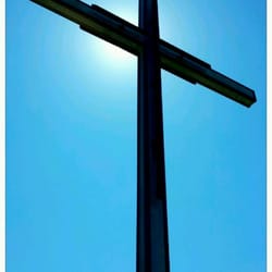 Journey Bible Church - OBC's cross backlit by the sun with blue sky.