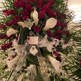 Flowers By Peter - A floral arrangement featuring red roses, white lilies, and lush green foliage, with a small note attached. - Nurseries & Gardening Near Me - Flushing, New York