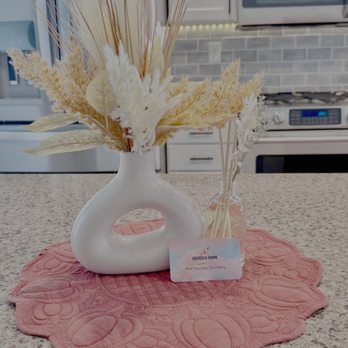 Haven & Home Central Oregon - A cozy kitchen vignette featuring a modern white vase with warm dried florals on a textured coral mat, styled with a Haven & Home Central OR - Home Cleaning Near Me Haven & Home Central Oregon - A cozy kitchen vignette featuring a modern white vase with warm dried florals on a textured coral mat, styled with a Haven & Home Central OR - Home Cleaning Near Me