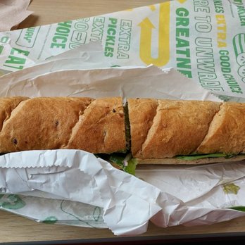 Subway - Veggie Delight Foot long on wheat... - A Subway veggie delight footlong sandwich on wheat bread, partially unwrapped, with visible lettuce and other vegetables inside. - Fast Food Near Me - Peru, Indiana