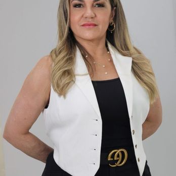 Studio D Brickell - A woman with blonde hair, wearing a white vest over a black top and black pants, stands with her hands behind her back... - Hair Salons Near Me - Miami, Florida Studio D Brickell - A woman with blonde hair, wearing a white vest over a black top and black pants, stands with her hands behind her back... - Hair Salons Near Me - Miami, Florida