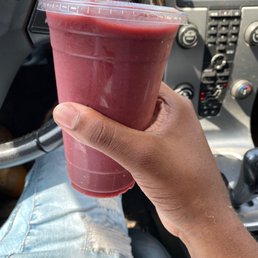 a hand holding a plastic cup with a smoothie in it
