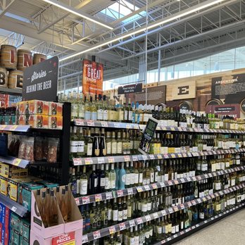 H-E-B - Holy alcohol, Batman! - A grocery store aisle features shelves stocked with various bottles of wine and liquor, with signage indicating deals and regions. - Drugstores Near Me - Lakeway, Texas