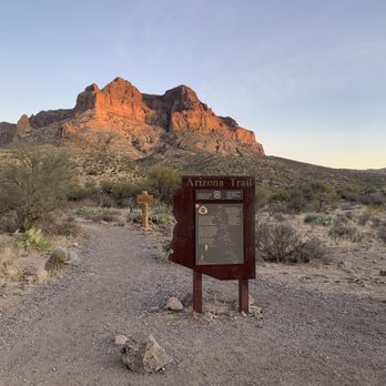 Picketpost Trail - A dirt trail sign for the Arizona Trail is situated in a desert landscape with sparse vegetation and mountains in the background. - Hiking Near Me