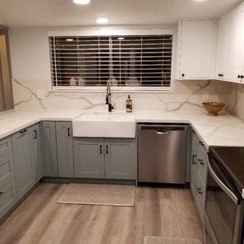 Madera Cabinets - A kitchen featuring gray lower cabinets, white marble countertops, and a large window with blinds above the sink, with stainless steel appliances. - Cabinetry Near Me - Mesa, Arizona