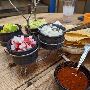 Potzolcano - a variety of condiments on a table - Mexican Near Me - Santa Ana, California