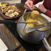 Photo of The Melting Pot - El Paso - El Paso, TX, United States. To the left of the cheese pot are dipping items, such as bread pieces, veggies, and green apple.