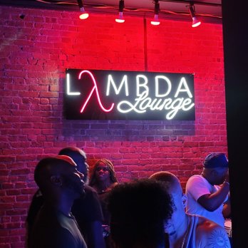 Lambda Lounge - a group of people standing in front of a neon sign - Gay Bars Near Me - New York, New York